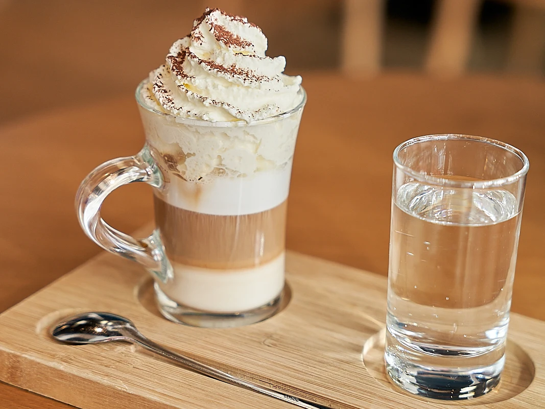 Latte Macchiato im Glas mit Milchschaum und Wasser serviert